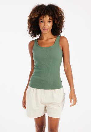 Green ribbed tank top with wide straps, rounded neckline, and textured fabric, paired with light beige shorts. Clear background.