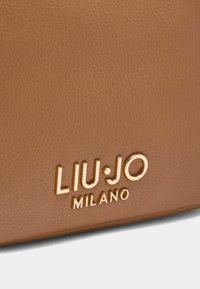 Brun læderhandtaske med prægede "LIU·JO MILANO" logo i guld. Har en tekstureret overflade og et slankt, rektangulært design.