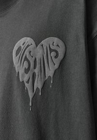 Sudadera gris con un gráfico en forma de corazón en un tono más oscuro, con un diseño goteante y una tipografía intrincada.