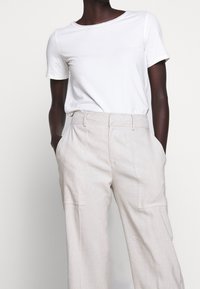 Vit kortärmad T-shirt och ljusbeige vida byxor med sidofickor. Mjukt tyg, avslappnad passform, minimalistisk design, inga synliga mönster.