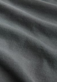 Tmavošedá, jemná tkanina s hladkým povrchom, s jemným rytmovaním a miernymi záhybmi, naznačujúca flexibilitu a schopnosť dobre padnúť.