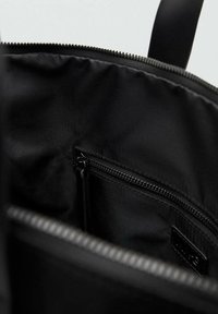 Intérieur de sac à dos noir avec tissu en nylon, poche zippée et texture lisse. Détails de fermeture éclair le long du bord supérieur.