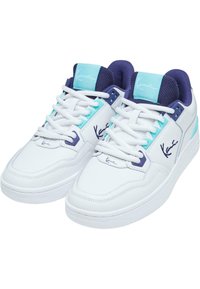 Vita sneakers med turkosa och lila accenter, med ett slätt läderöverdrag, meshtunga och platta snören. Logotyp synlig på sidan.