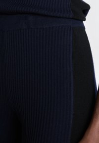 Leggings a coste con un design a blocchi di colore in blu navy scuro e nero. Il tessuto ha una finitura morbida e leggermente testurizzata.