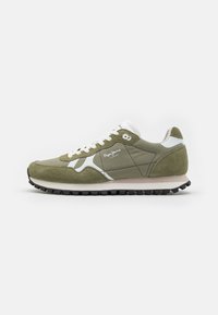 Zapatillas de deporte verde olivo con parte superior de ante y malla, acentos blancos, puntera redonda y suela de goma negra con tacos de tracción.