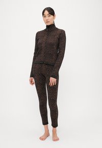 Čierna súprava z látky pozostávajúca z priliehavého dlhého rukávu s dvojcestným zipsom a legín, zdobená hnedým leopardím vzorom a pásom s logom značky.