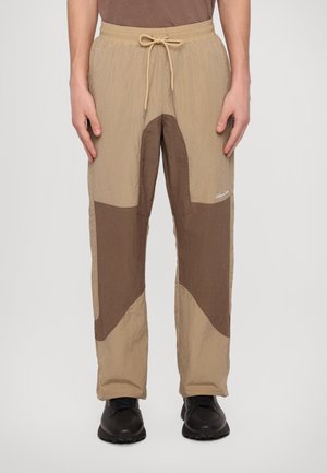 Beige and brown men's pants with a textured finish, featuring a contrasting star-shaped design and an adjustable drawstring waist.