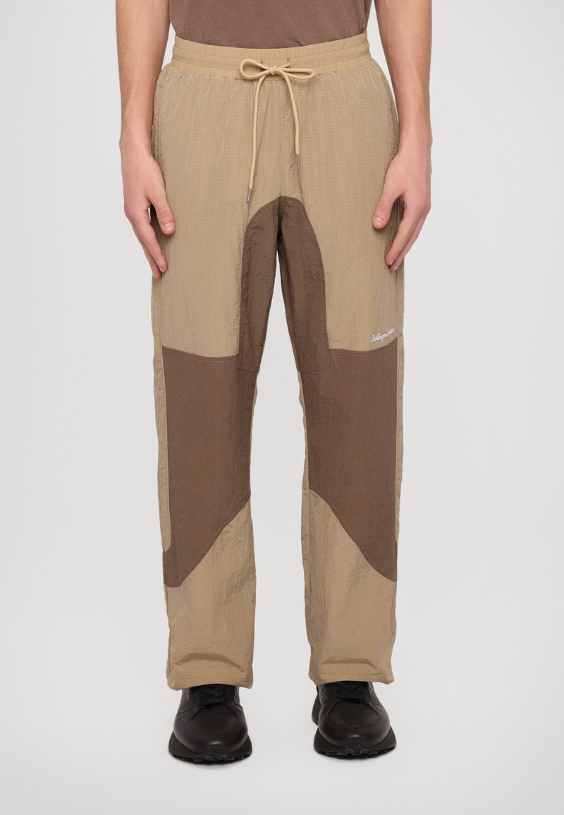 Beige og brune bukser til mænd med en struktureret finish, der har et kontrasterende stjernedesign og en justerbar snøring i taljen.