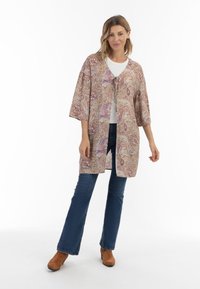 Kimono cu model paisley, din material ușor, cu mâneci largi, deschis în față și închidere cu legătură. Purtați peste un top alb și blugi evazați.