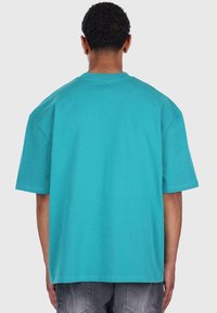Turkusowy, oversize'owy t-shirt wykonany z miękkiej bawełny, z krótkimi rękawami, okrągłym dekoltem i gładką teksturą. Idealny na codzienne wyjścia.