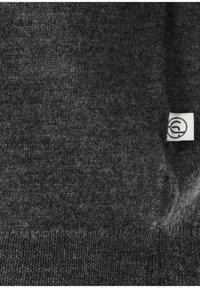 Dunkelgrauer Strickstoff mit einem kleinen weißen Etikett auf der rechten Seite, das ein schwarzes rundes Logo zeigt.