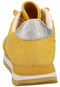 Yellow fabric sneaker with textured surface, white sole, and silver accent at the heel. Features a sporty design with a cushioned collar.