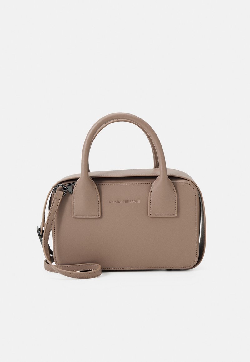 Liten beige handväska i slät läder, med två rundade handtag upptill, en avtagbar axelrem och präglad logotypdetalj.