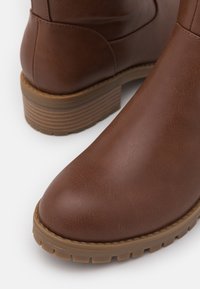 Ruske antilopija zimske čizme sa okruglim vrhom, teksturiranom površinom i niskim složenim đonom koji ima utore.