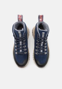 Blå mocka vandringskängor med grå foder, silverdetaljer och svarta gummisulor. Utrustad med metalöglor och dekorativa snören.