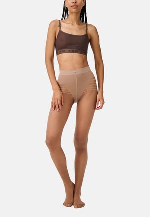 Top sportivo marrone con fascia logata, abbinato a leggins nudi a vita alta con strisce orizzontali a taglio. Tessuto liscio e elastico.