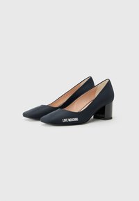 Navy blue high-heeled pumps with a black block heel display "LOVE MOSCHINO" logo on the side against a plain white background.