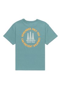 Camiseta de algodón color teal con un gráfico circular que presenta árboles blancos y texto naranja. La impresión en la parte posterior dice: "Recuerda, solo tú puedes prevenir incendios forestales."