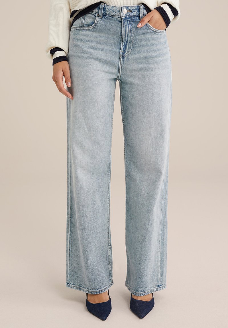 Jeans de pierna ancha en azul claro con una cintura alta, con cinco bolsillos y un acabado desgastado. La tela tiene una apariencia suave y ligeramente texturizada.