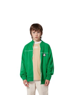 Groene ritsjack met witte accenten, gemaakt van zachte stof. Bevat een logo op de linkerborst en een beige t-shirt eronder.