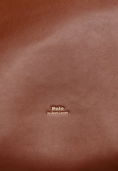 Brązowa powierzchnia ze skóry z tłoczonym na złoto napisem Polo by Ralph Lauren wyśrodkowanym na niej.