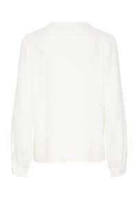 Chemise blanche à manches longues présentant un tissu texturé, une coupe décontractée, un col rond, et des poignets à boutons avec des fentes sur les manches.
