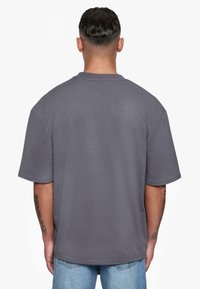 Grå oversized T-shirt med rund hals og korte ærmer, lavet af blødt materiale. Har enkle sømdetaljer og en afslappet pasform.
