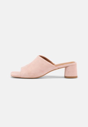 Open-toe roze suède mule met een lage blokhak en instapontwerp op een neutrale achtergrond.