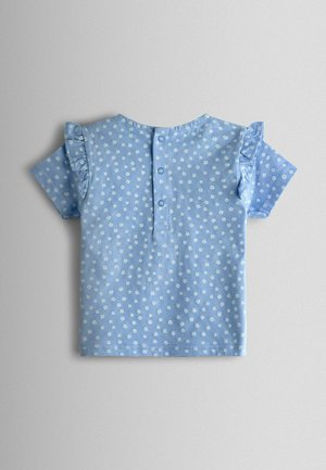 Blaues Baumwolloberteil mit kurzen Ärmeln, weißem Blumenmuster und Rüschendetails, Knopfverschluss an der Rückseite, glatte Textur.