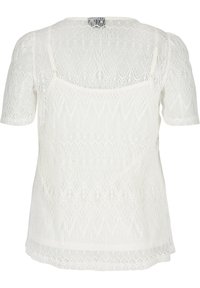 Top bianco in pizzo con maniche corte, caratterizzato da un motivo testurizzato e un collo rotondo. L'orlo ha un delicato bordo in pizzo.