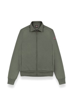 Zielona oliwkowa kurtka zapinana na zamek, wykonana z miękkiego materiału, z kołnierzem stojącym, ściągaczami na rękawach oraz okrągłym logo na lewym rękawie.