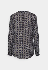 Blus med långa ärmar i marinblå tyg som har ett geometriskt mönster med ljusa cirklar i olika storlekar, knapphål bak och elastiska ärmslut.