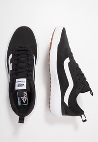 Black sneakers with a breathable mesh upper, white side stripes, and rubber outsole. Features include a padded tongue and pull tab at the heel.