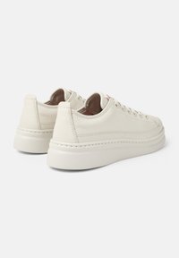 Sneakers bianchi in pelle con finitura testurizzata, punta rotonda e suola in gomma spessa. Presentano dettagli di cucitura e lacci minimalisti.