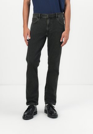 Jeans de mezclilla gris oscuro con corte recto, bolsillos frontales visibles y detalles cosidos, combinados con zapatos negros de cordones.