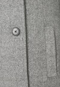 Cappotto grigio in lana con tessuto testurizzato, un bottone nero con un motivo a croce e una tasca laterale. Design classico con rever strutturati.