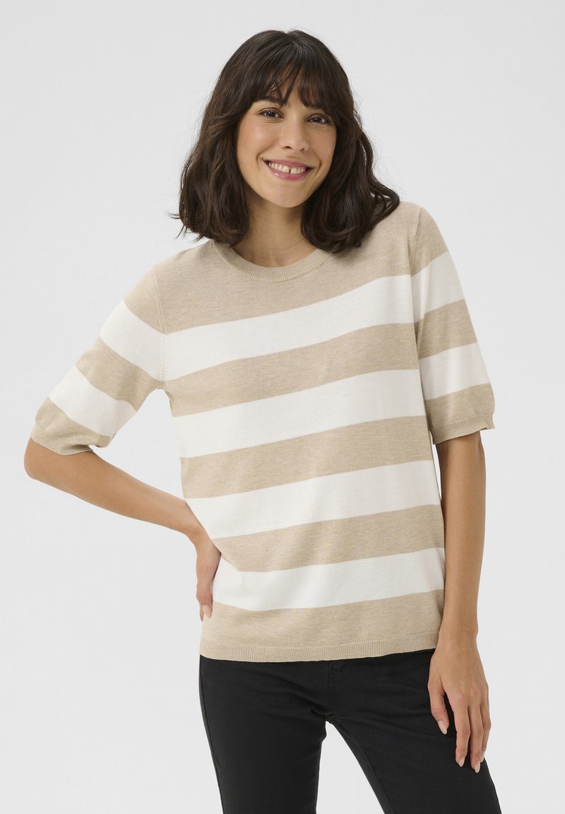 Pull à rayures beige et blanches avec des manches courtes, encolure ronde, texture tricotée et ourlet côtelé, associé à un pantalon noir.