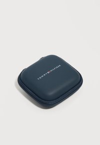 Συμπαγές θήκη με φερμουάρ σε ναυτικό μπλε χρώμα με το λογότυπο Tommy Hilfiger σε λευκό και κόκκινο στην κορυφή, τοποθετημένη σε απλό ανοιχτό φόντο.