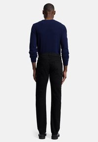 Marineblauwe crewneck trui gecombineerd met zwarte jeans. De jeans hebben een slim fit en zijn gemaakt van denim. Zwarte laarzen maken de outfit af.