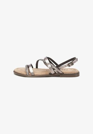 Sandalias metálicas plateadas con tiras trenzadas, suela plana y hebilla ajustable en el tobillo. Textura suave del plantillo en color beige.