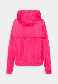 Różowa lekka kurtka z kapturem, elastycznymi mankietami i dołem. Gładki, błyszczący materiał; posiada dużą tylną część dla wentylacji.