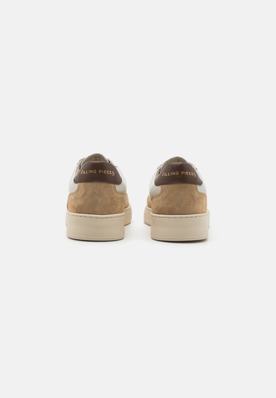 Beige ruskind og hvide lædersneakers med en tan hæltab. "Filling Pieces" logo indprentet i guld på hælen. Lave sneakers.