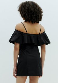 Schwarzes Off-Shoulder-Kleid mit gerafftem Oberteil, dünnen verstellbaren Trägern, taillierter Passform und einem Saum, der über dem Knie endet. Glatte Stofftextur.