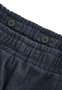 Marineblåt herringbone-stof med struktureret overflade, prydet med to sorte knapper og elastisk talje for justerbar pasform.