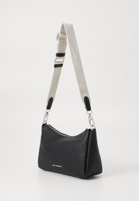 Borsa a mano in pelle nera con finitura texturizzata, forma curvata e una tracolla staccabile beige con accessori in argento. Chiusura superiore con cerniera.