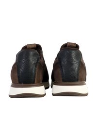 Zapatos de ante marrón con acentos texturizados en negro, con una suela blanca. La parte trasera muestra una asa de tirón y un sutil detalle de costura.