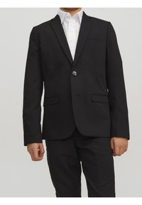 Czarna marynarka z pojedynczym zapięciem na guzik, slim fit, z klapami i dwoma przednimi kieszeniami. Noszona na białej koszuli z kołnierzykiem.