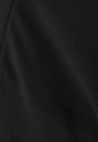 Čierny látkový vzor s hladkou textúrou, ktorý obsahuje kombináciu ryhých a plochých častí, ukazujúcich rôznu lesklosť a hĺbku farby.