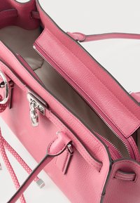 Ροζ τσάντα χειρός από δέρμα με υφή, με ασημένιο φερμουάρ και μεταλλικά στοιχεία. Το εσωτερικό έχει λείο επένδυση, με ρυθμιζόμενο λουρί και πλευρικές λεπτομέρειες.