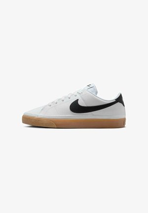 Baskets blanches basses avec le logo Nike noir et une semelle en caoutchouc brun, vues de profil sur un fond blanc.